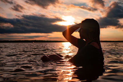 Silhouette woman on beach against sky during sunset