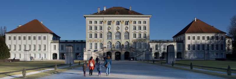 People walking in front of buildings against clear sky