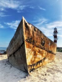 Abandoned boat on beach against sky