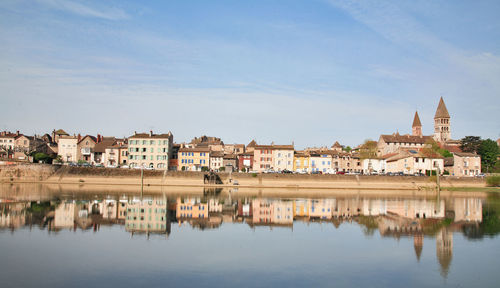 Reflection of buildings in lake against sky in city