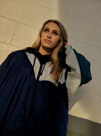 Portrait of beautiful young woman standing against wall