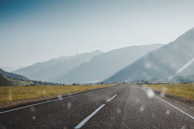 Road leading towards mountains against sky