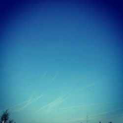 Low angle view of vapor trails in blue sky