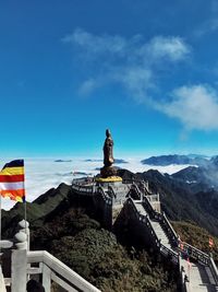Man standing by statue on mountain against sky