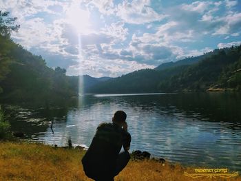 Rear view of man on lake against sky