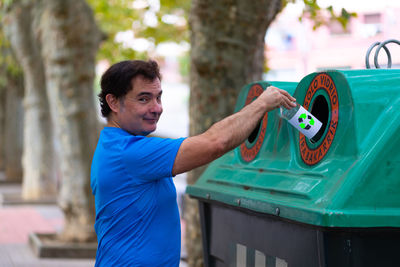 Portrait of man throwing bottle in garbage bin