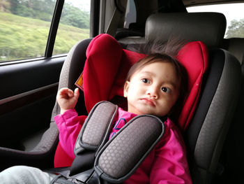 Close-up of cute baby girl sitting in car