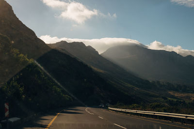Road leading towards mountains against sky