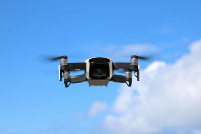 Low angle view of drone flying against blue sky