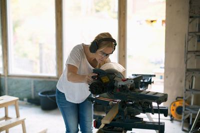 Woman cutting wood with circular saw during home improvement