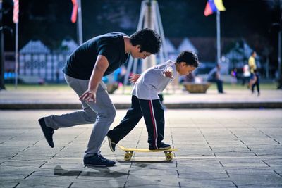 Side view of coach teaching student balancing on skateboard at park