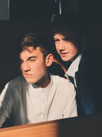 Close-up of young men looking away by wooden table