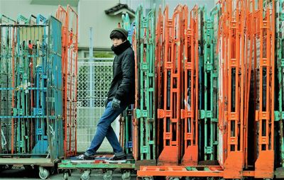 Side view portrait of teenage boy standing by carts