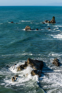 Scenic view of tasman sea against sky with waves crashing against rocks 