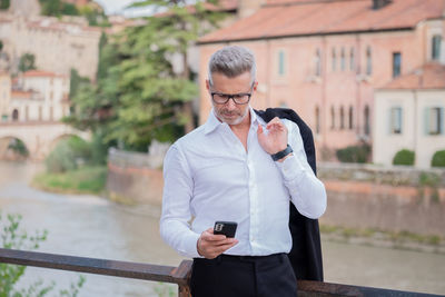 Businessman using mobile phone while standing outdoors