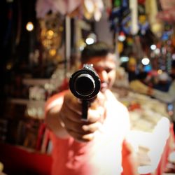 Man holding gun while standing in amusement park at night