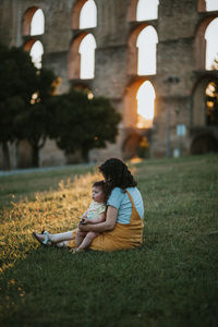 Mother and daughter on field during sunset