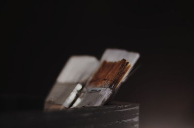 Close-up of paintbrushes on table against black background