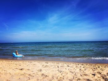 Rear view of woman in inflatable ring at beach