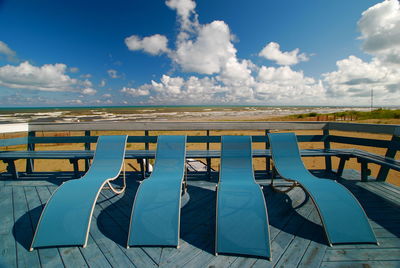 Empty chairs against cloudy sky