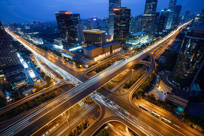 High angle view of illuminated city street amidst buildings at night