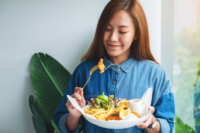 Closeup image of a beautiful asian woman eating fish and chips on table in the restaurant