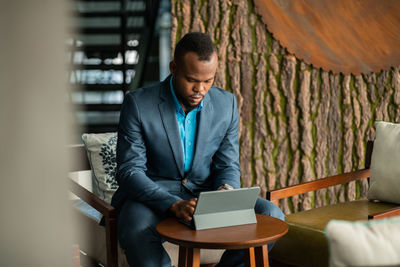 Young man using mobile phone while sitting on table