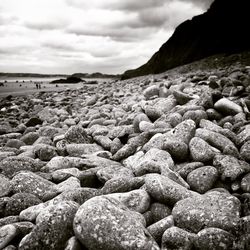 Rocks on shore against cloudy sky