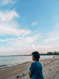 Rear view of man looking at sea against sky