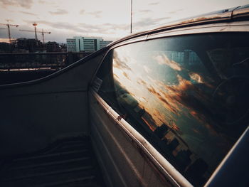 Reflection of cloudy sky on car window during sunset