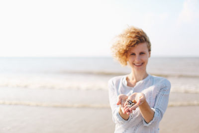 Portrait of young woman showing seashells