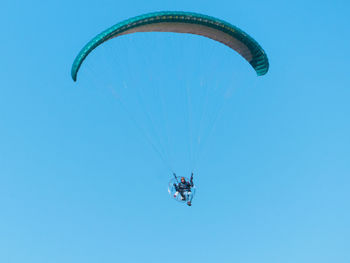 Low angle view of person paragliding against clear blue sky