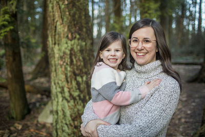 Young mother wearing glasses holds her cute daughter.