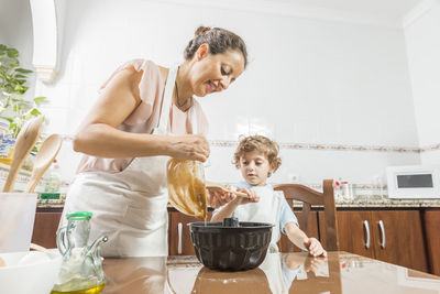 Boy assisting mother preparing food at home