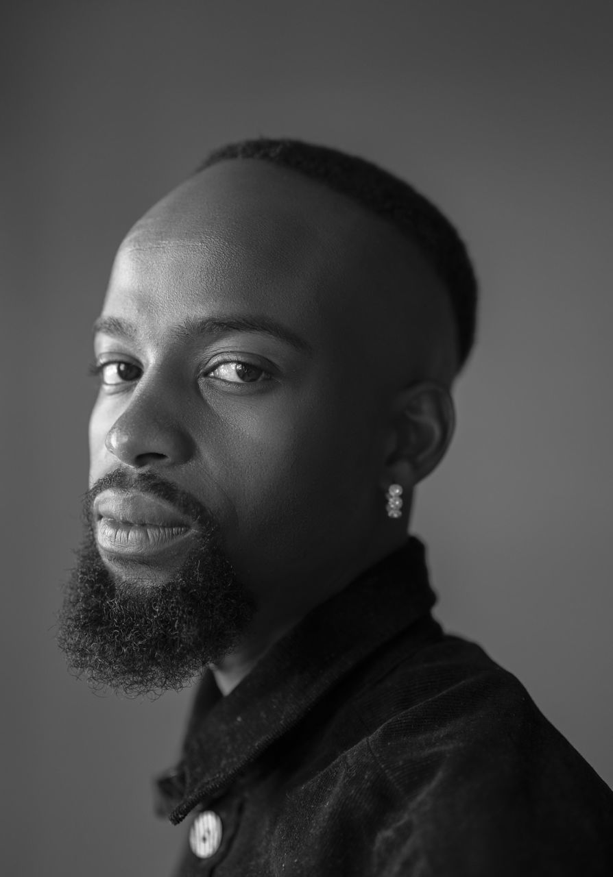 headshot, portrait, one person, looking away, young adult, indoors, studio shot, looking, lifestyles, real people, smiling, close-up, young men, clothing, casual clothing, front view, emotion, contemplation