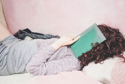 Woman reading book on bed at home