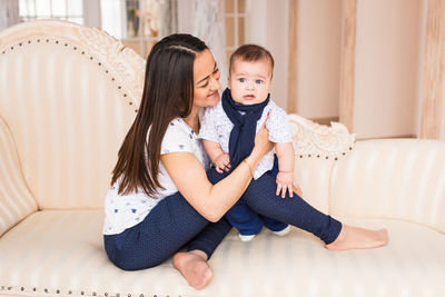 Full length of mother and baby sitting at home