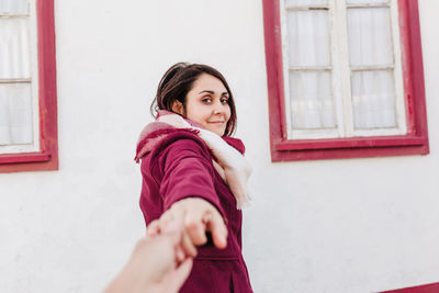 Happy holding hand to camera.colorful houses.promenade costa nova, aveiro. follow me