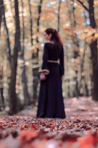 Woman standing by leaves in forest
