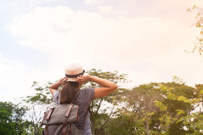 Low angle view of young woman using smart phone against sky