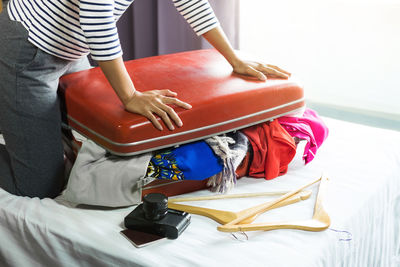 Midsection of woman packing suitcase on bed at home