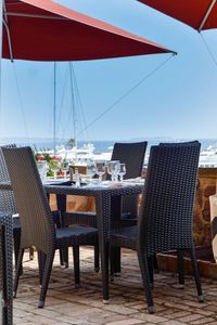 Chairs and tables at restaurant by sea against sky