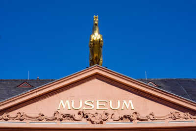 Low angle view of text on building against clear blue sky