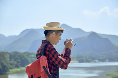 Man wearing hat against mountains against sky