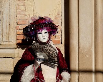 Portrait of mature woman wearing costume while holding hand fan during venice carnival