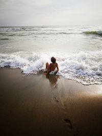 Rear view of shirtless man in sea against sky