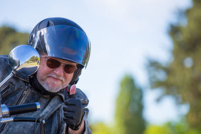 Portrait of senior man showing thumbs up while wearing crash helmet