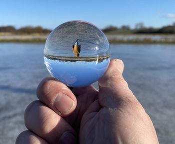 Midsection of person holding crystal ball in lake