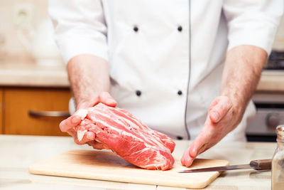 Midsection of man working on cutting board