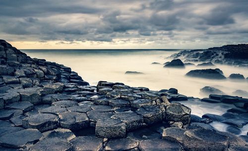 Rocks on sea shore against sky